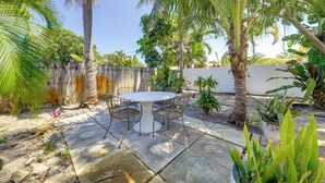 A patio with a round table and chairs, surrounded by palm trees and potted plants. - 1 Mi to Sand! Deerfield Beach Home w/ Patio (Deerfield Beach)