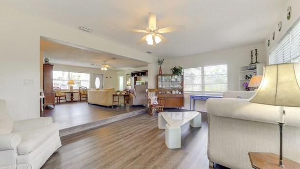 A spacious living room with a large sofa, a coffee table, and a dining area with chairs and a table. - 1 Mi to Sand! Deerfield Beach Home w/ Patio (Deerfield Beach)