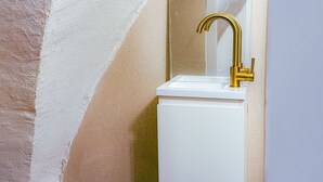 A bathroom with a white sink, gold faucet, and a mirror. - roga bjeruslem (Jerusalem)