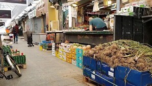 A market with various stalls selling goods, including a large pile of root vegetables. - roga bjeruslem (Jerusalem)