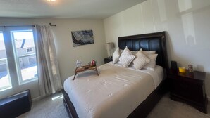 A neatly arranged bedroom with a large bed, a bedside table, a nightstand, a window with curtains, and a ceiling light. - Charming pet friendly mountain views . Hottub included (Colorado Springs)