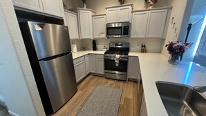 A modern kitchen with stainless steel appliances, white cabinetry, and a patterned rug. - Charming pet friendly mountain views . Hottub included (Colorado Springs)