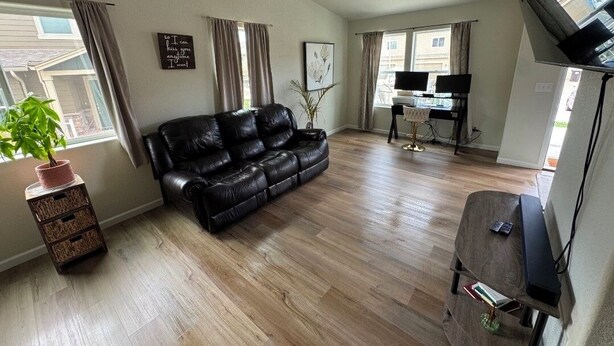 A living room with a leather sofa, a small wooden table, a TV, and a desk with a computer. - Charming pet friendly mountain views . Hottub included (Colorado Springs)