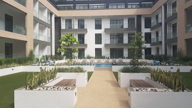 Un bâtiment moderne doté d’une cour intérieure, d’un espace extérieur aménagé pour s’asseoir et d’une piscine.