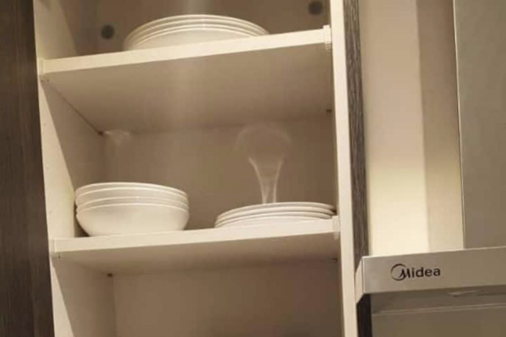 Une cuisine avec des meubles blancs et un appareil électroménager de la marque Midea.
