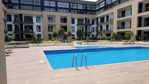 Un bâtiment moderne doté d’une piscine, de nombreux balcons et d’un jardin aménagé.