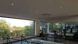 Une salle de sport moderne, dotée de grandes fenêtres et d’équipements d’exercice.