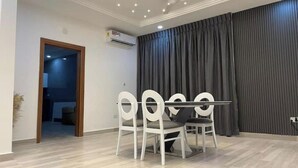 A dining area with a table and chairs, a ceiling fan, recessed lighting, and a large window with curtains.
