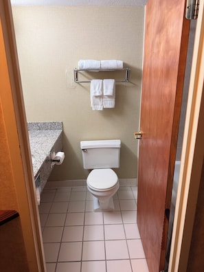 Ein Badezimmer mit Toilette, Handtuchhalter mit Handtüchern und einem Papiertuchspender.