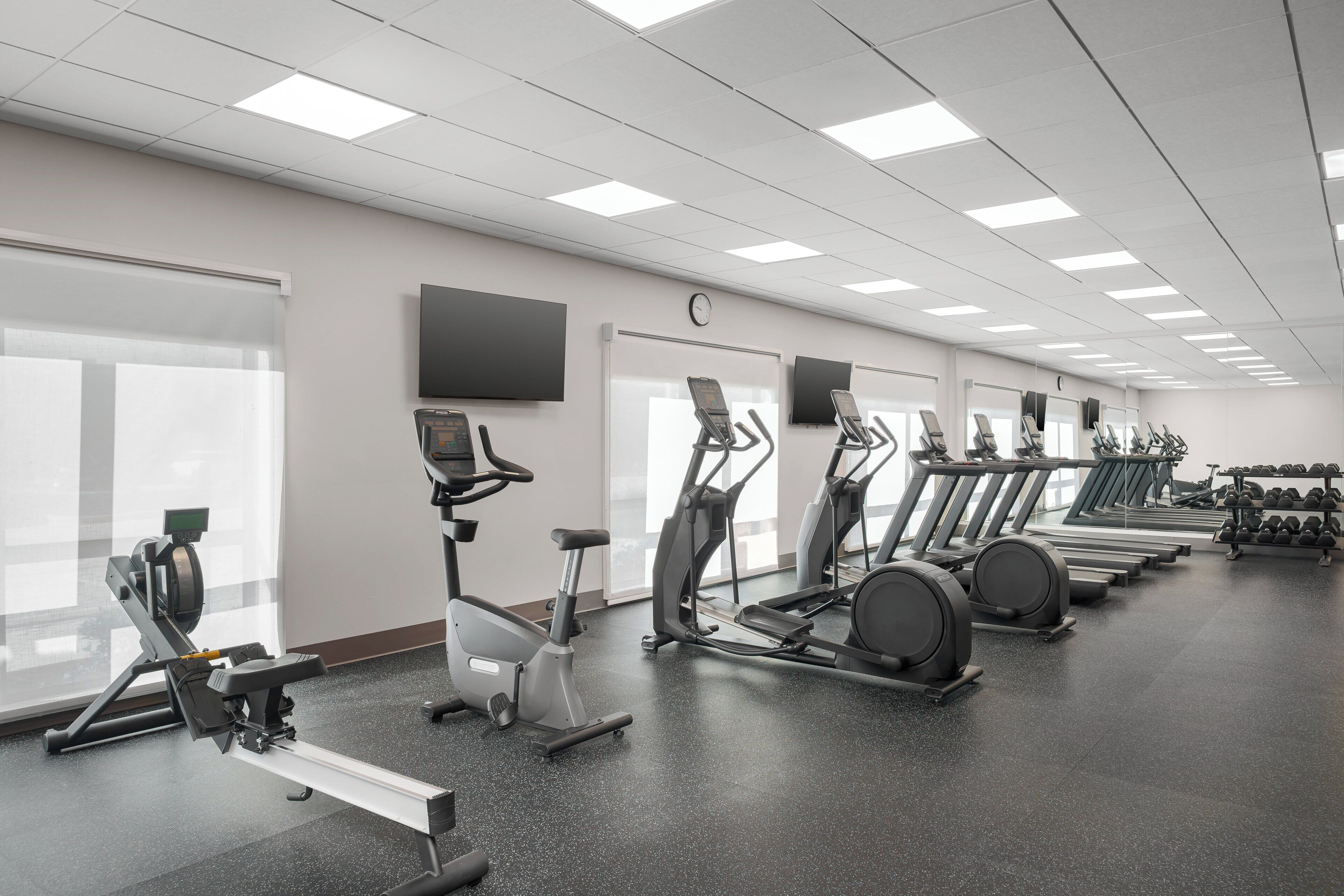 Un gimnasio con bicicletas estáticas, cintas de correr y mancuernas.