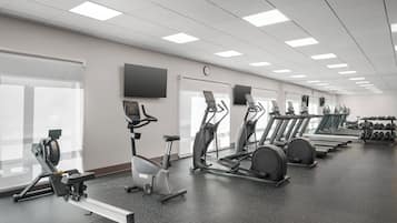 Un gimnasio con bicicletas estáticas, cintas de correr y mancuernas.