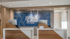 A reception desk with a blue and white geometric wall design, a wooden reception desk, and a sign indicating 'Holiday Inn Express & Suites.'