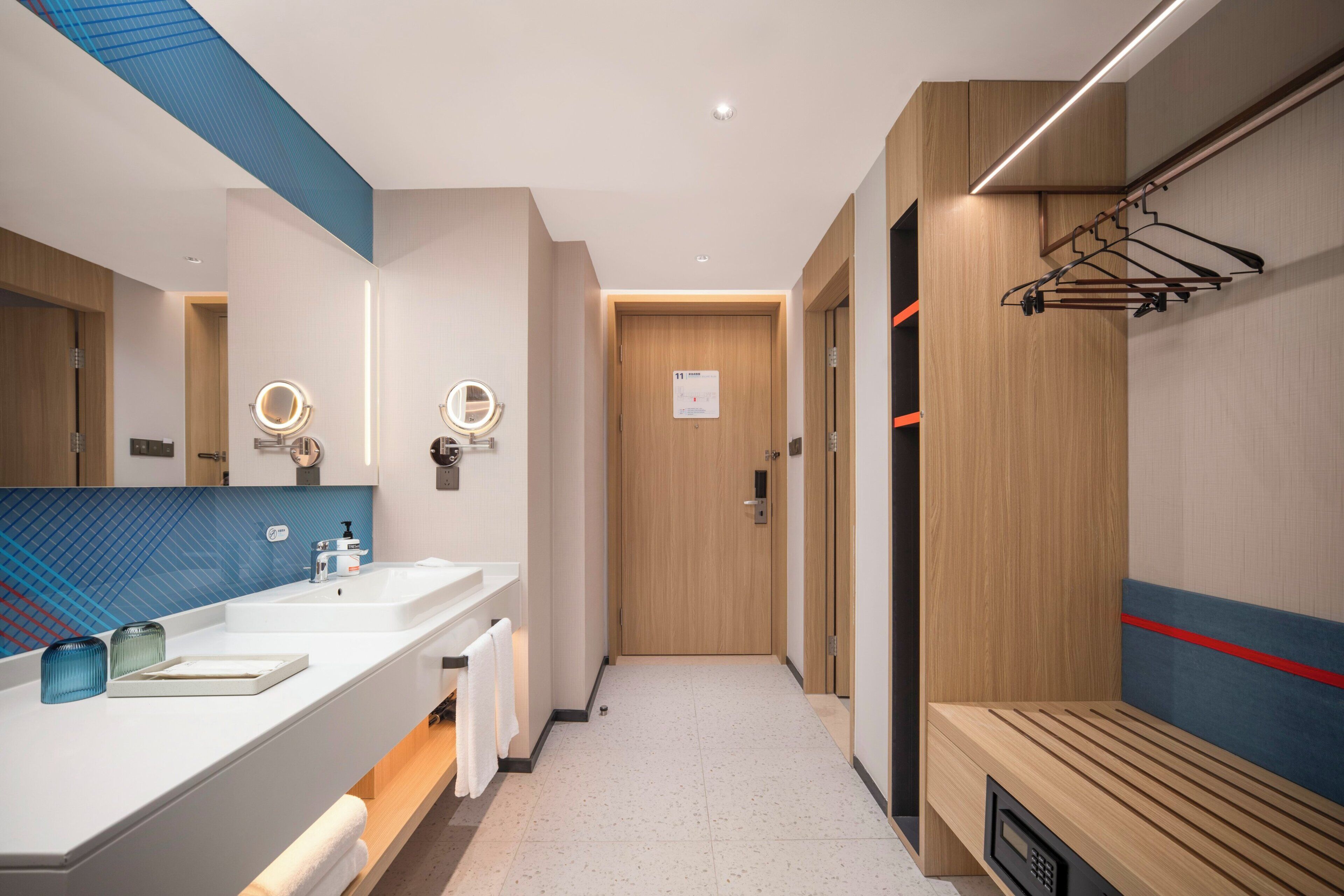 A modern bathroom with a vanity, mirror, and towel rack.