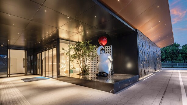A modern building entrance with a glass facade, a large white sculpture, and a red balloon. - Holiday Inn Express Beijing Tongzhou by IHG (Tongzhou)