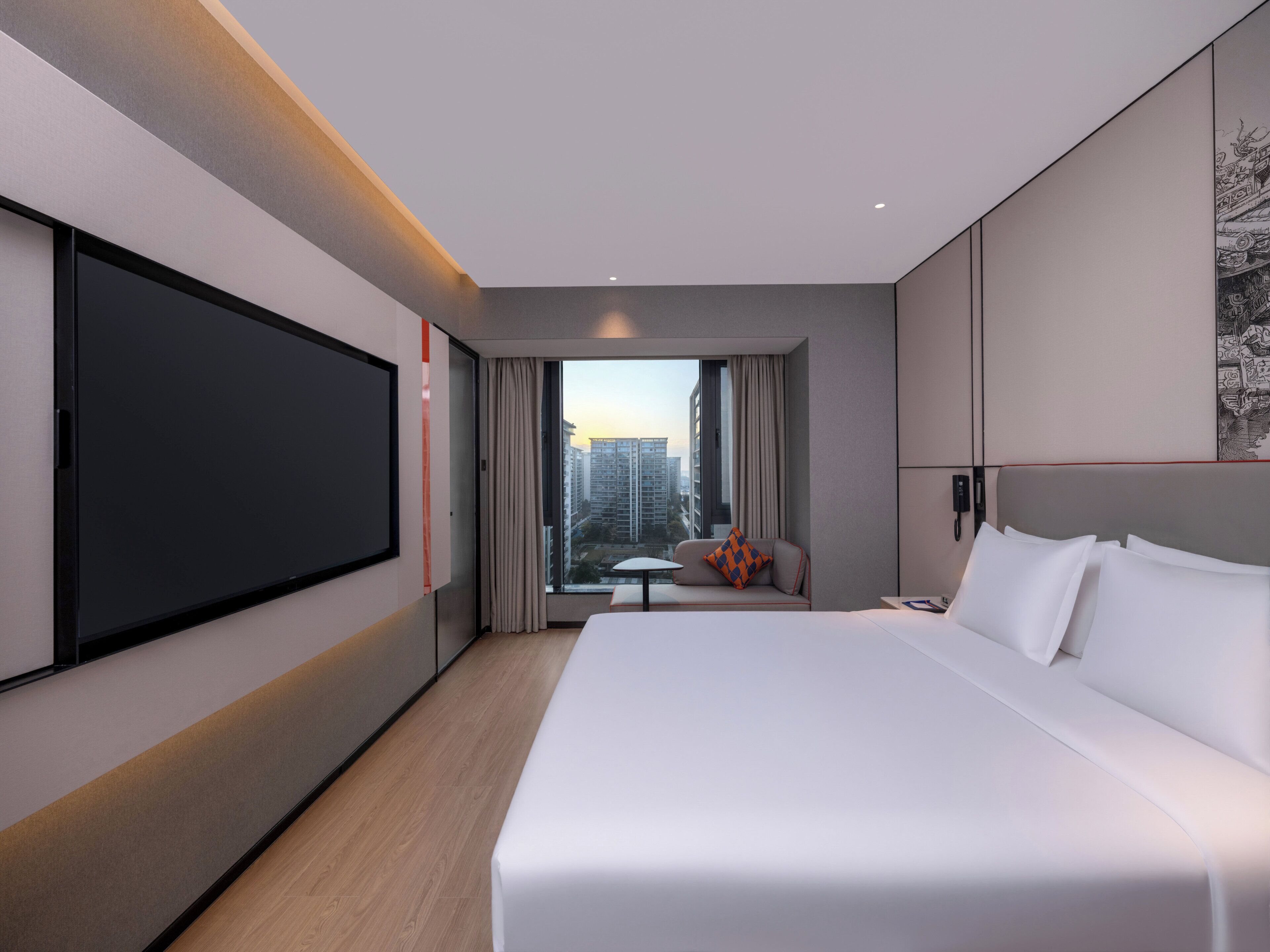 Een moderne hotelkamer met een groot bed, een flatscreen televisie, een tafeltje en uitzicht op de stad.