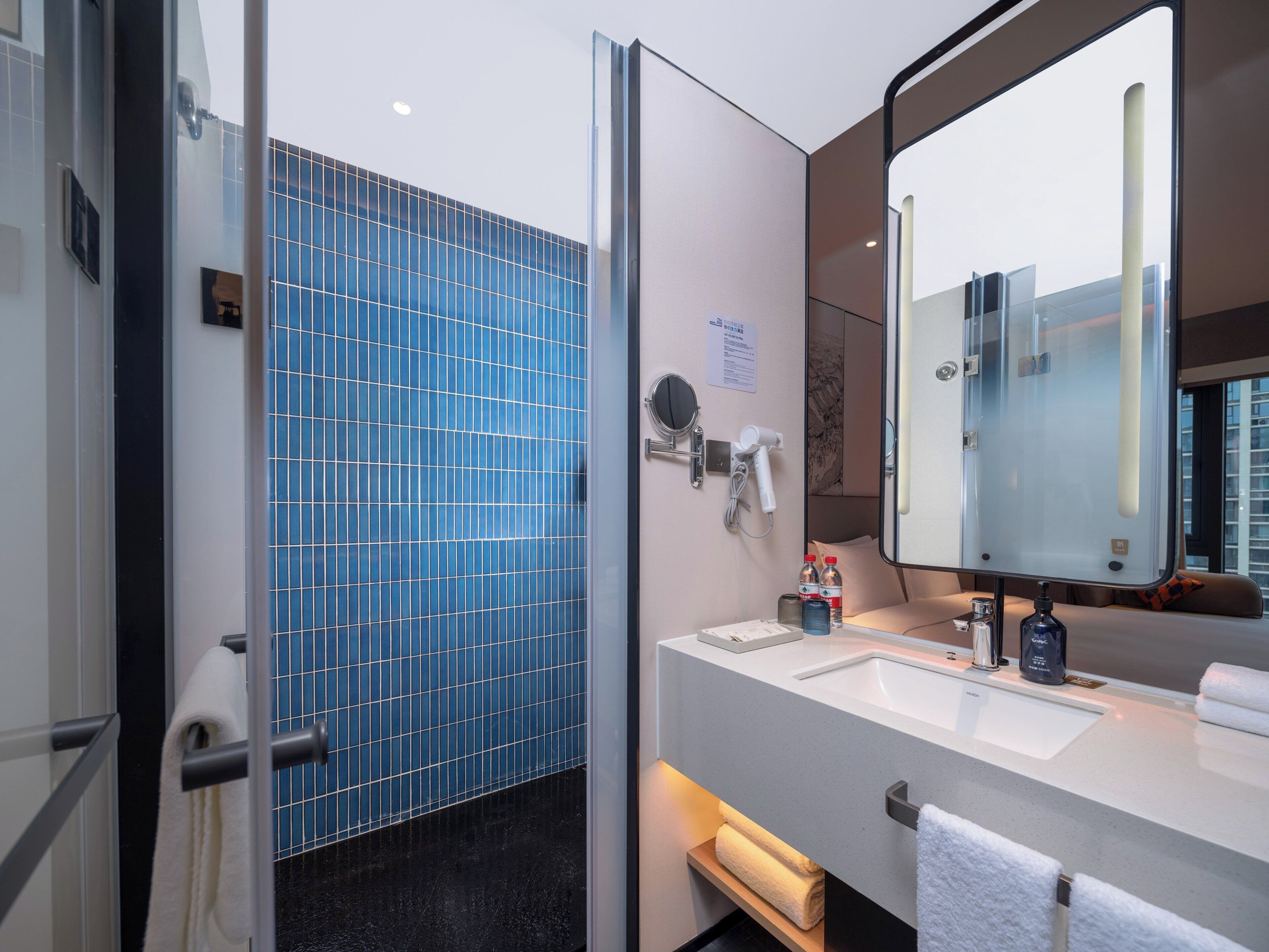 A modern bathroom with a large mirror, a sink, and a towel rack.