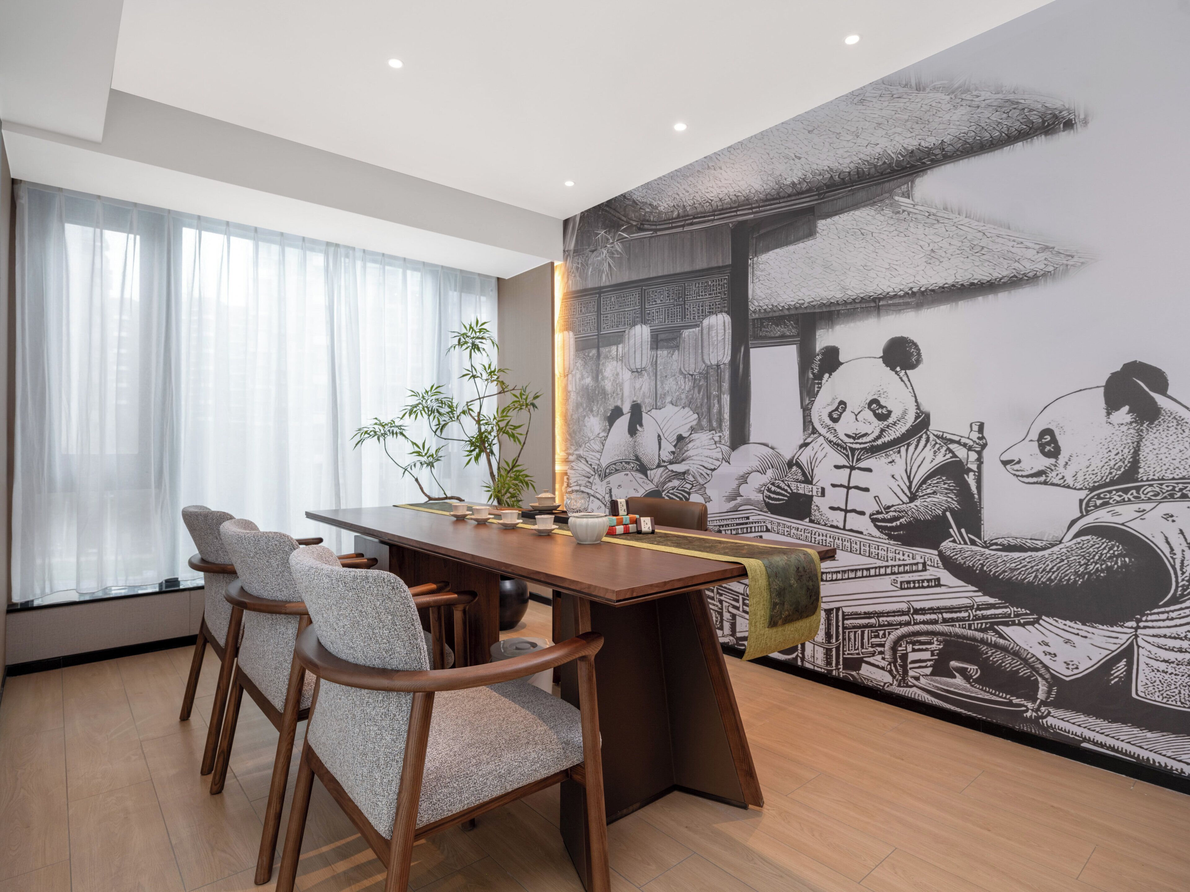 Un comedor con mesa de madera, sillas y un mural de pandas.