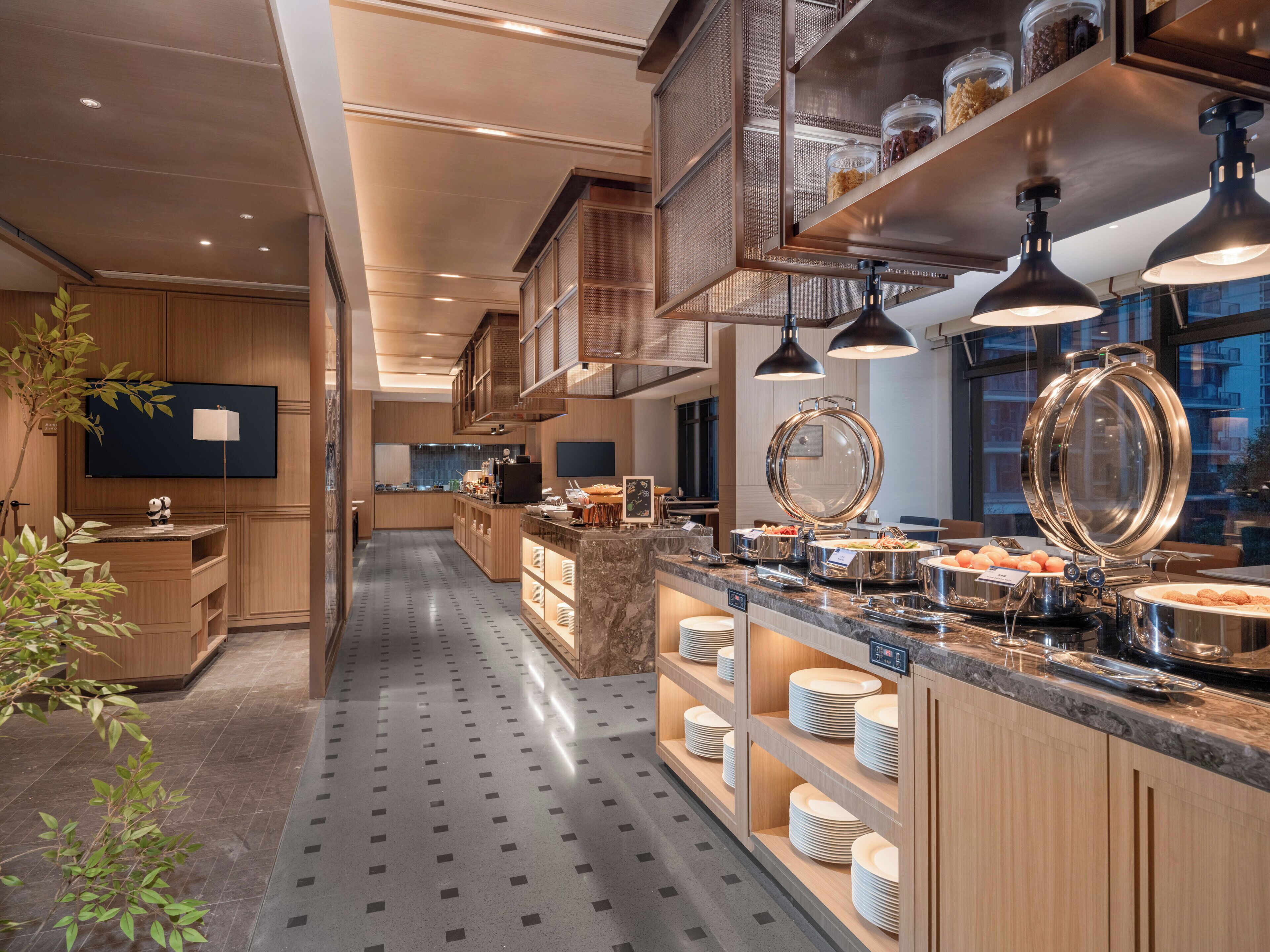 Une cuisine moderne dotée d’un long comptoir, d’appareils électroménagers en acier inoxydable et d’une grande fenêtre.