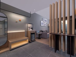 A modern hotel room with a sofa, a small coffee table, a desk with a computer, a mini-fridge, and a decorative wall with framed pictures. - Holiday Inn Express Chengdu Shuangliu Chuanda Road by IHG (Chengdu)