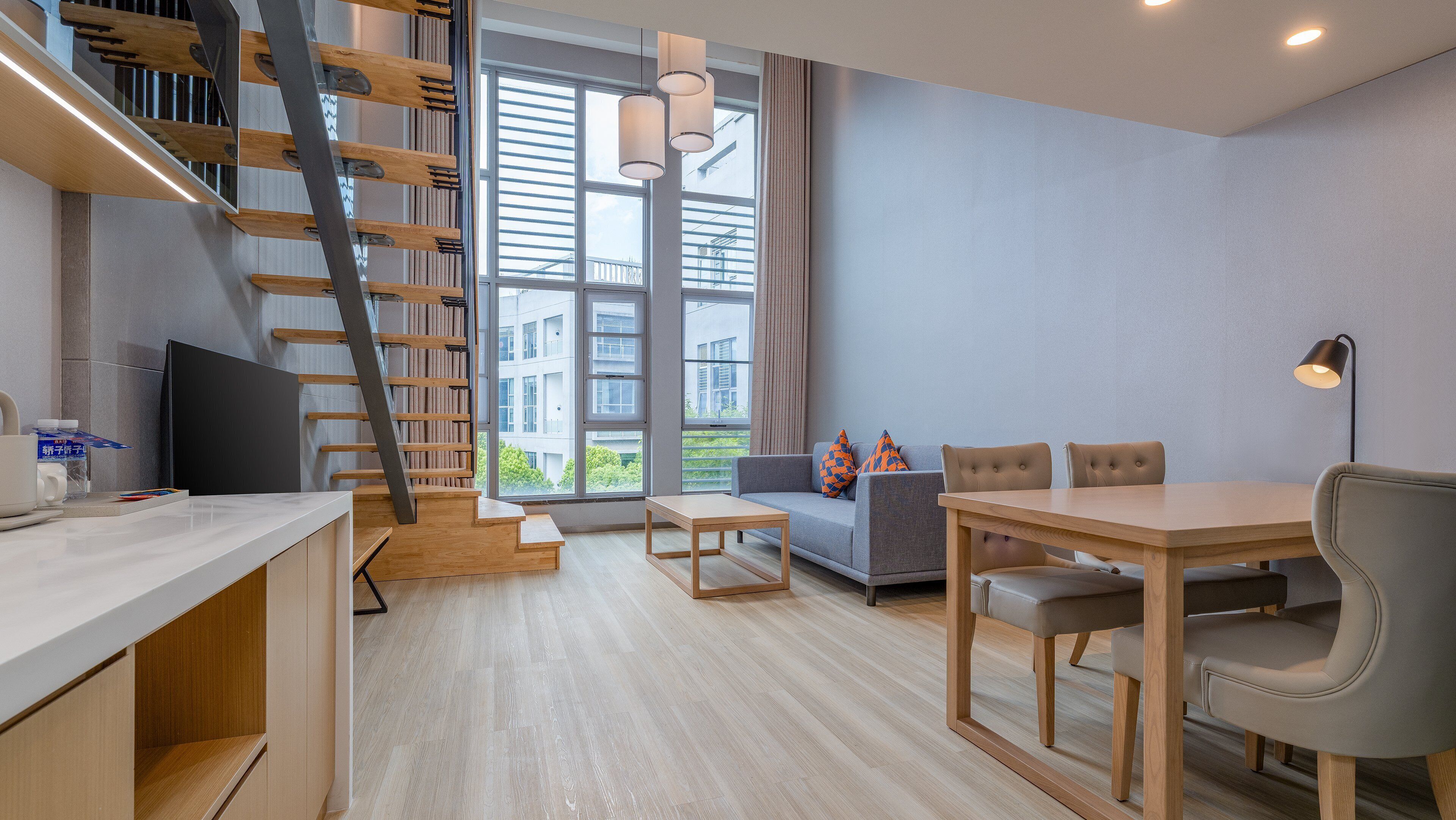 A modern living space with a staircase, a sofa, a dining table, and a TV.