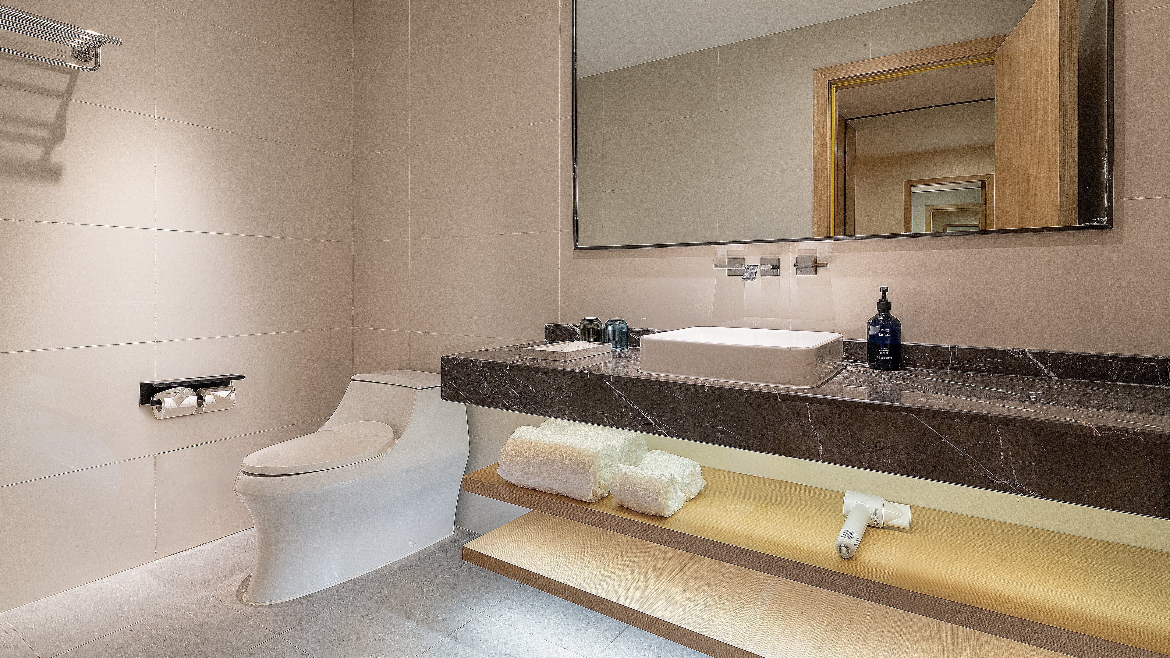 A modern bathroom with a toilet, sink, mirror, and towel rack.