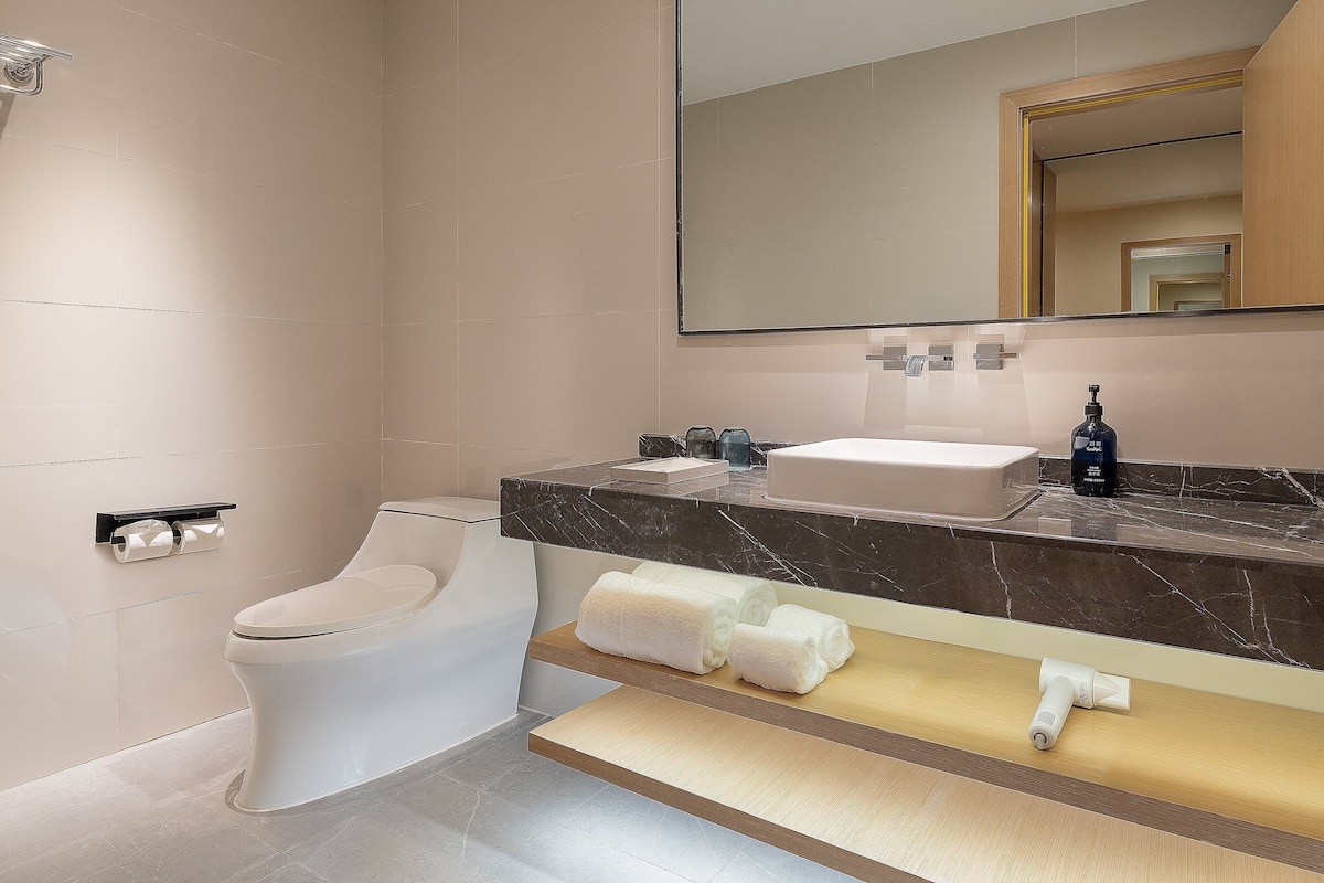 A modern bathroom with a toilet, sink, mirror, and towel rack.