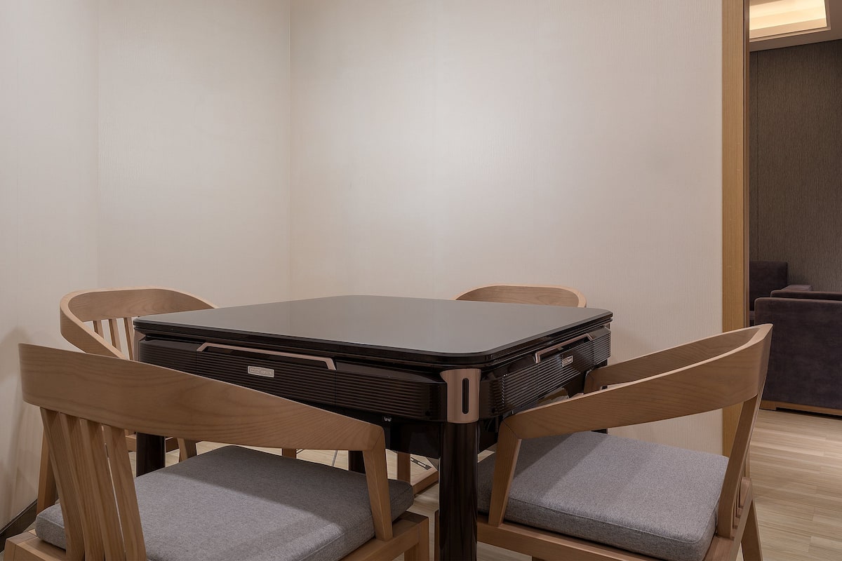A compact room with a table and four chairs, a sofa, and a door leading to another area.