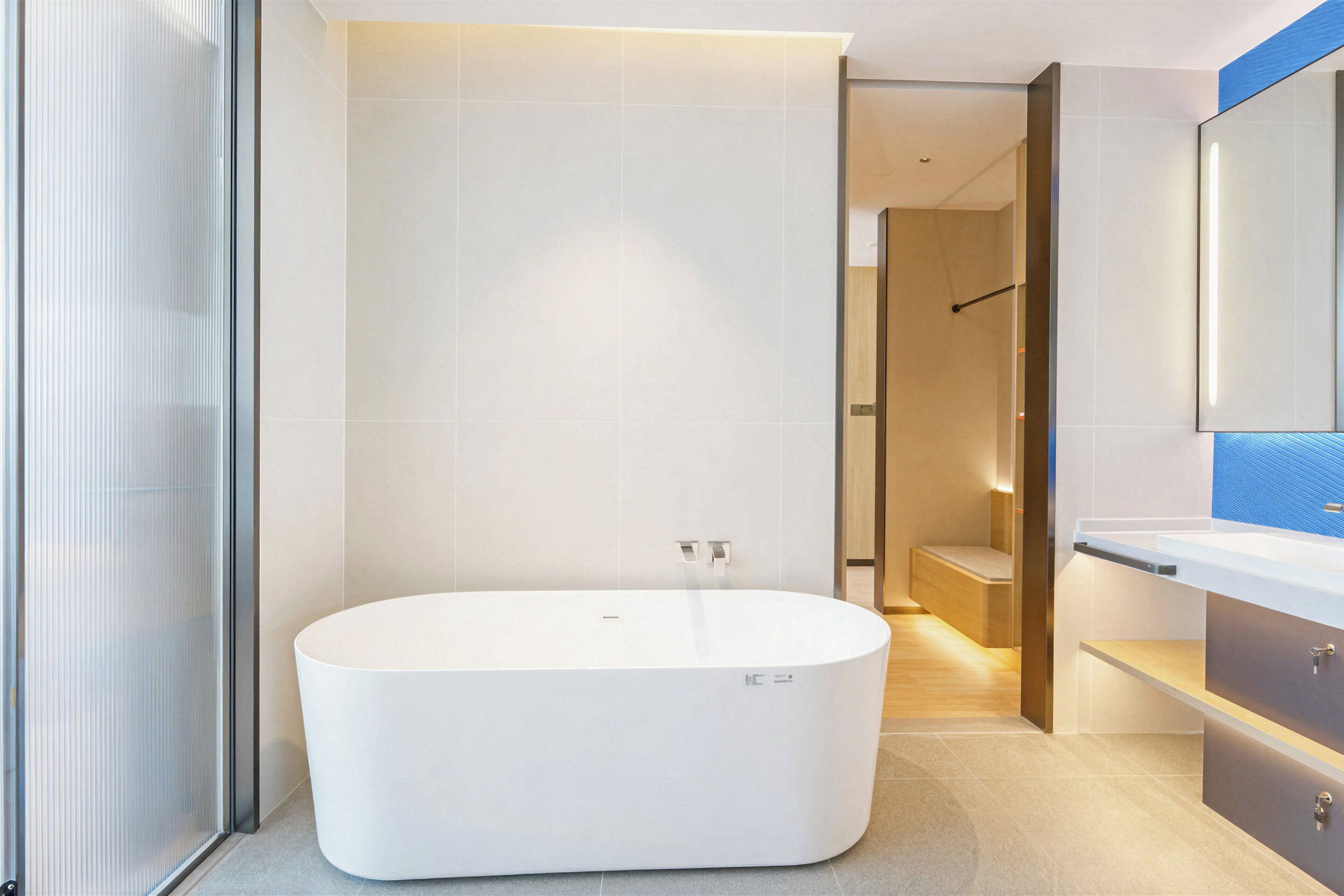 A modern bathroom with a freestanding bathtub, a wooden bench, and a large mirror.