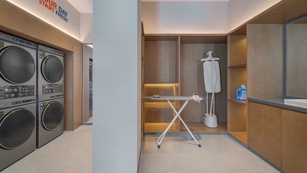 A laundry room with multiple washing machines, an ironing station, and a wall-mounted drying rack. - Holiday Inn Express Changbaishan Beauty Pine by IHG (Yanbian)
