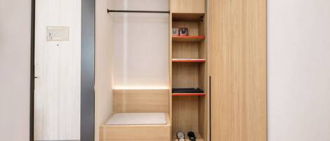 Un dressing avec un banc, des étagères et un porte-chaussures.