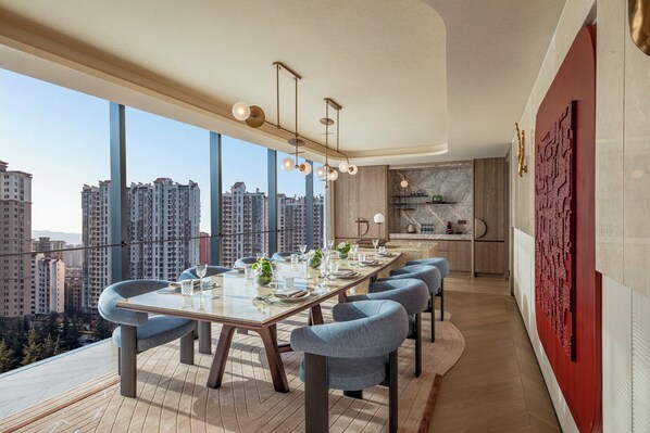 Un espace repas moderne avec une longue table, des chaises et une vue sur la ville.