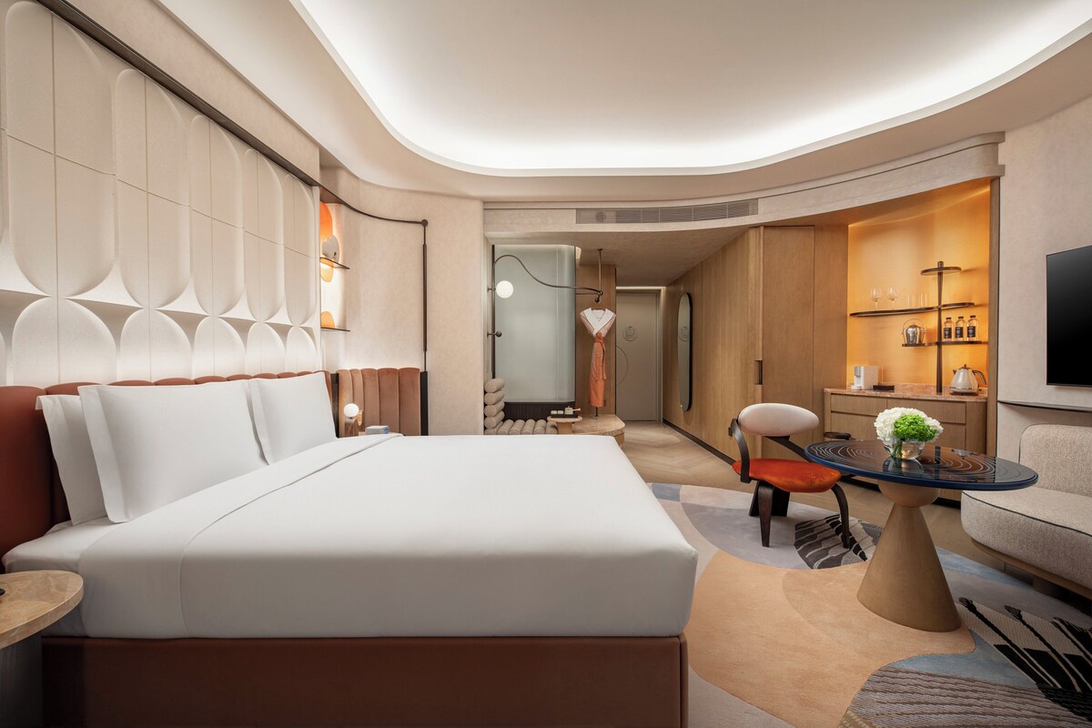 Een moderne hotelkamer met een groot bed, een zithoek met een tafel en een televisie.