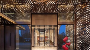 A modern hotel entrance with a glass door, a red sculpture, and a ceiling with a patterned light design. - Hotel Indigo Xi An High Tech Zone by IHG (Xi'an)