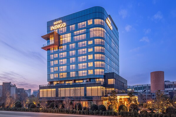 A modern hotel with a curved facade, multiple floors, and illuminated windows. - Hotel Indigo Xi An High Tech Zone by IHG (Xi'an)