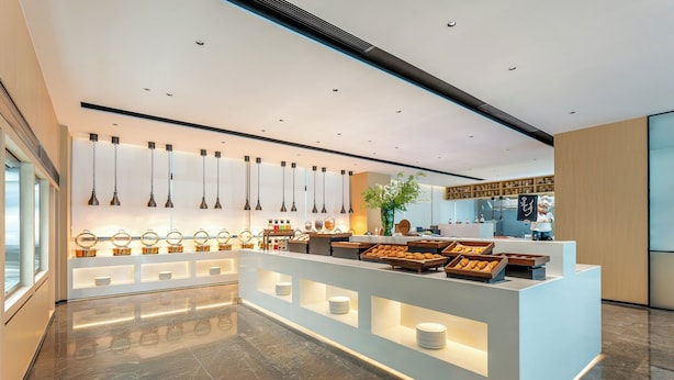 A modern hotel lobby with a central reception desk, glass display cases, and pendant lighting. - Holiday Inn Suzhou North by IHG (Suzhou)