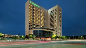 A modern hotel with a curved glass facade, multiple floors, and illuminated signage. - Holiday Inn Suzhou North by IHG (Suzhou)
