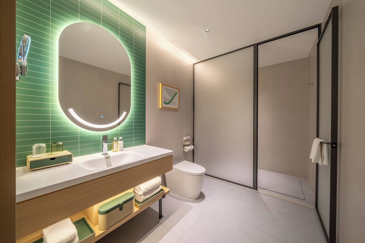Ein modernes Badezimmer mit großem Spiegel, Waschbecken, Toilette und Duschbereich.