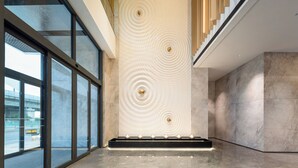 A modern interior with a large glass window, a wall with circular patterns, and a staircase with wooden steps. - Holiday Inn Suzhou North by IHG (Suzhou)