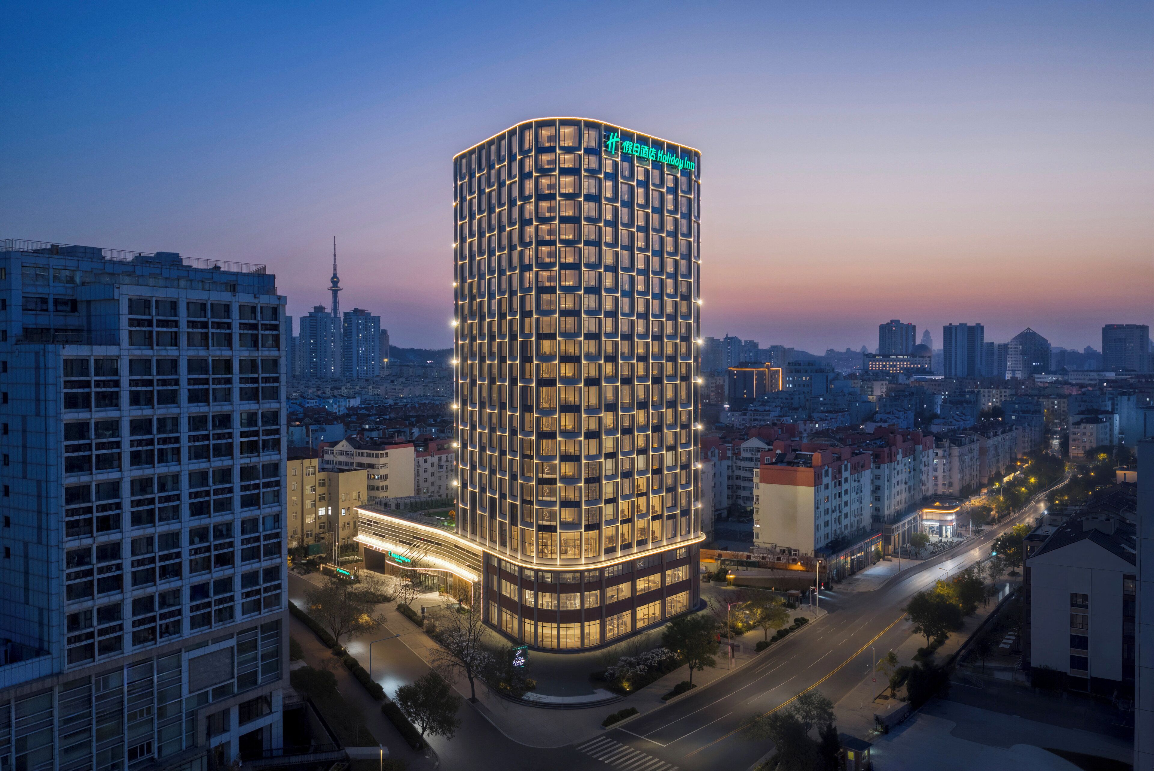 A modern hotel with a curved facade, multiple floors, and illuminated windows.