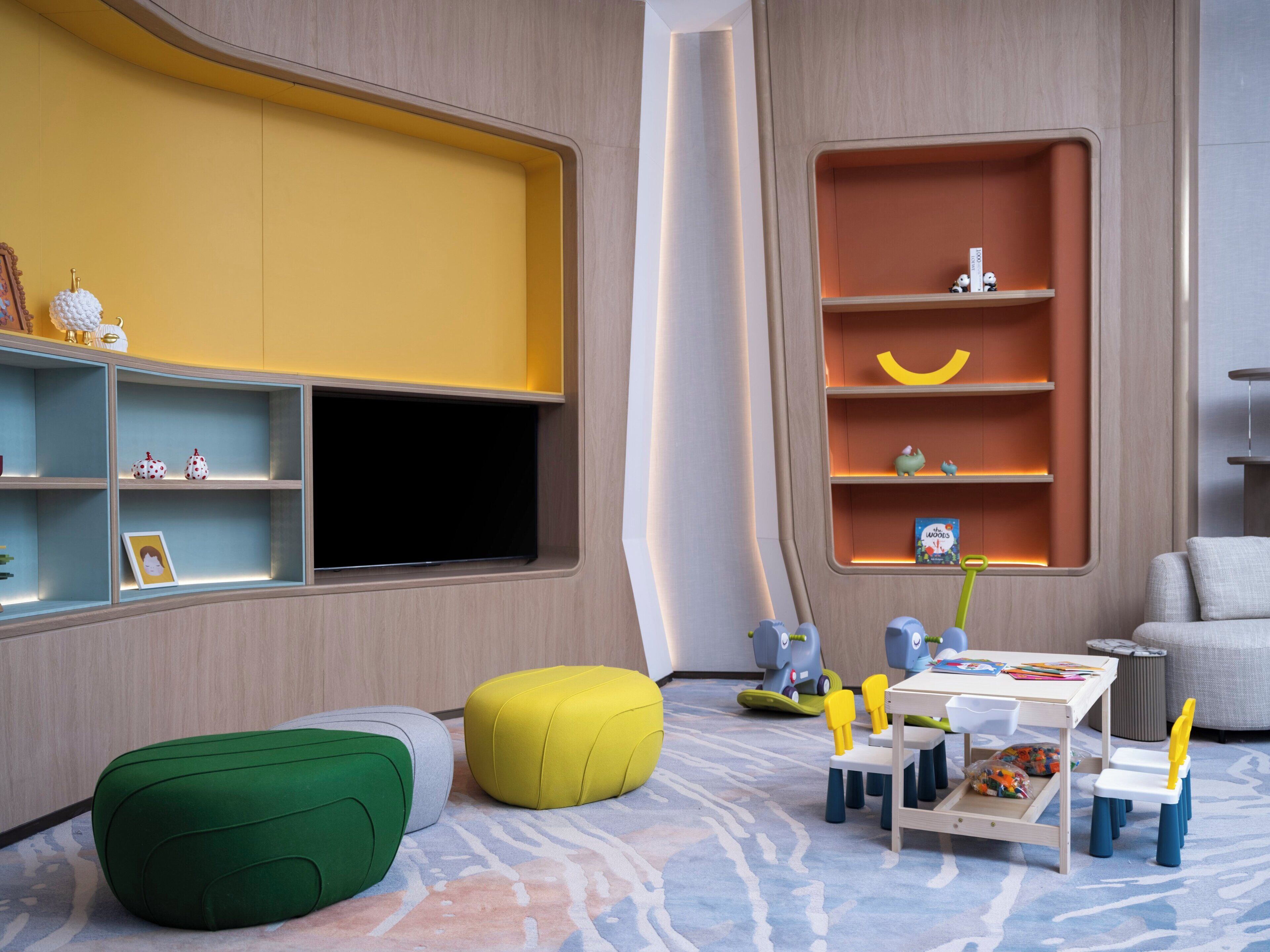 A modern child's playroom with a large window, built-in shelves, and a small table with toys.