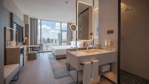 A modern hotel room with a large bed, a desk, a bathroom with a large mirror, and a view of the city. - Holiday Inn Qingdao CBD by IHG (Qingdao)