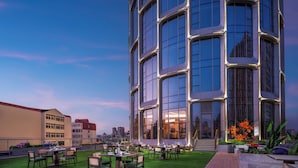 A modern building with a rooftop dining area featuring outdoor seating and a well-maintained lawn. - Holiday Inn Qingdao CBD by IHG (Qingdao)