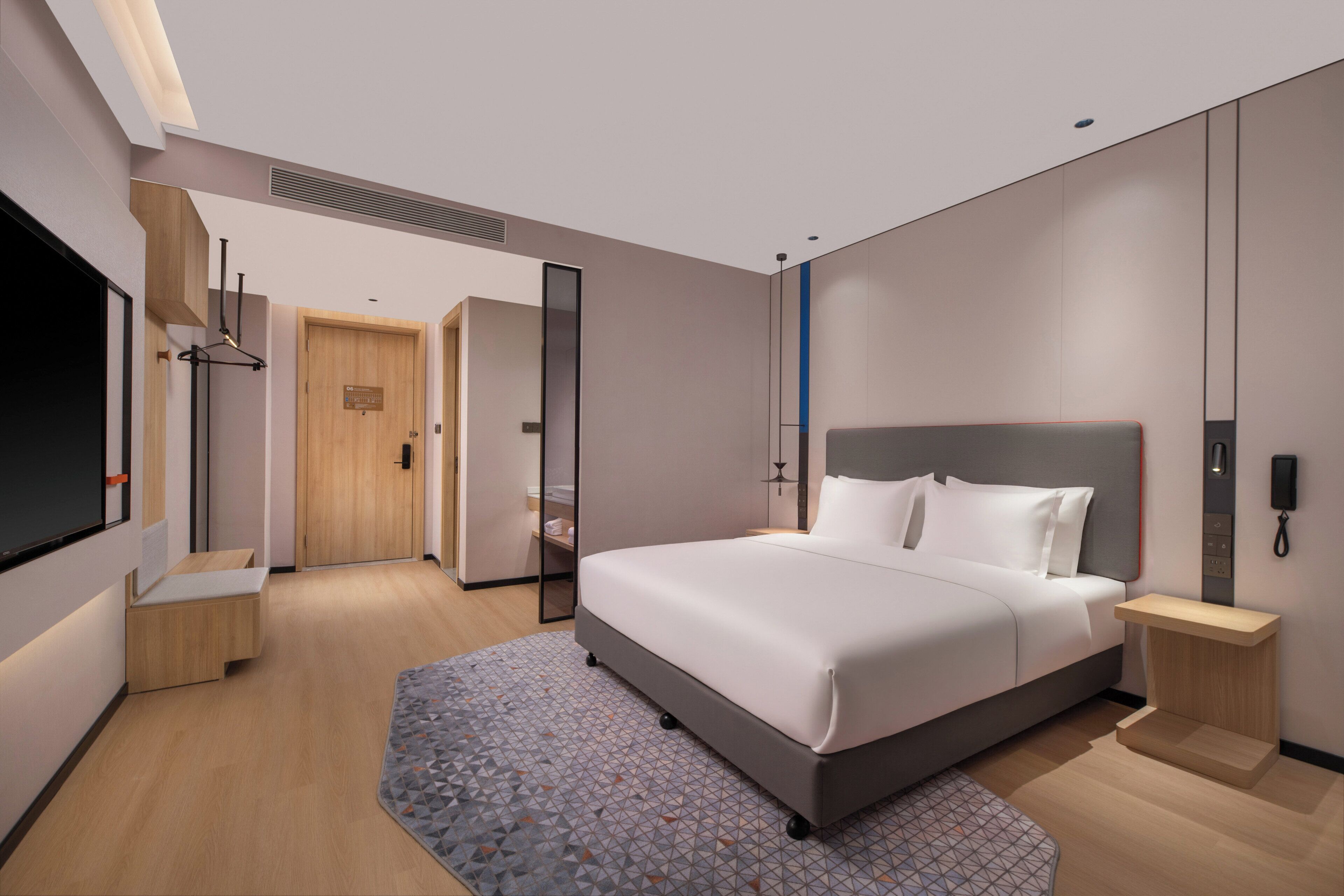 Una habitación de hotel moderna con una cama grande, mesitas de noche, un televisor de pantalla plana y un vestidor.