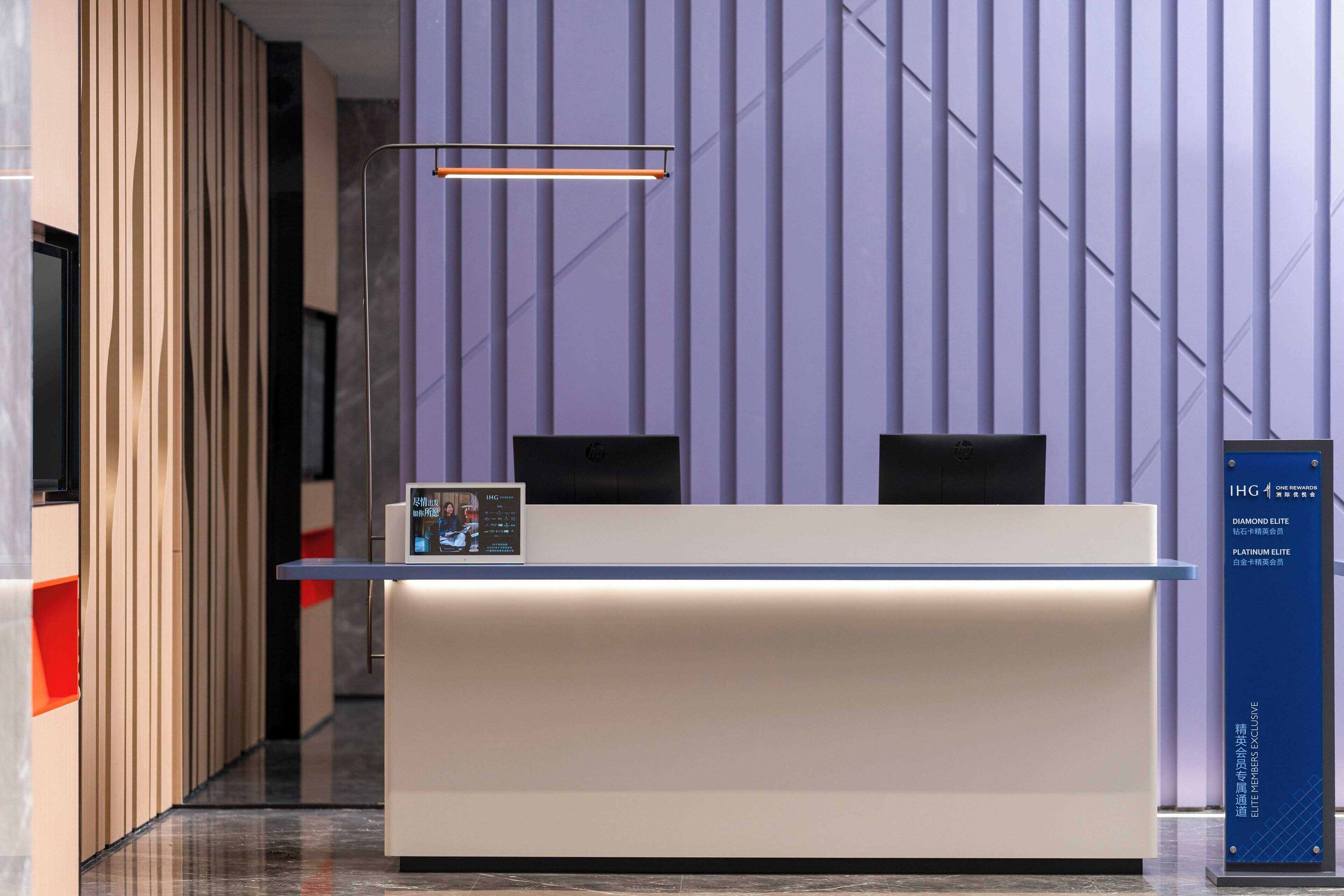 Balcão de atendimento com tela digital, placa azul e design de interiores moderno.