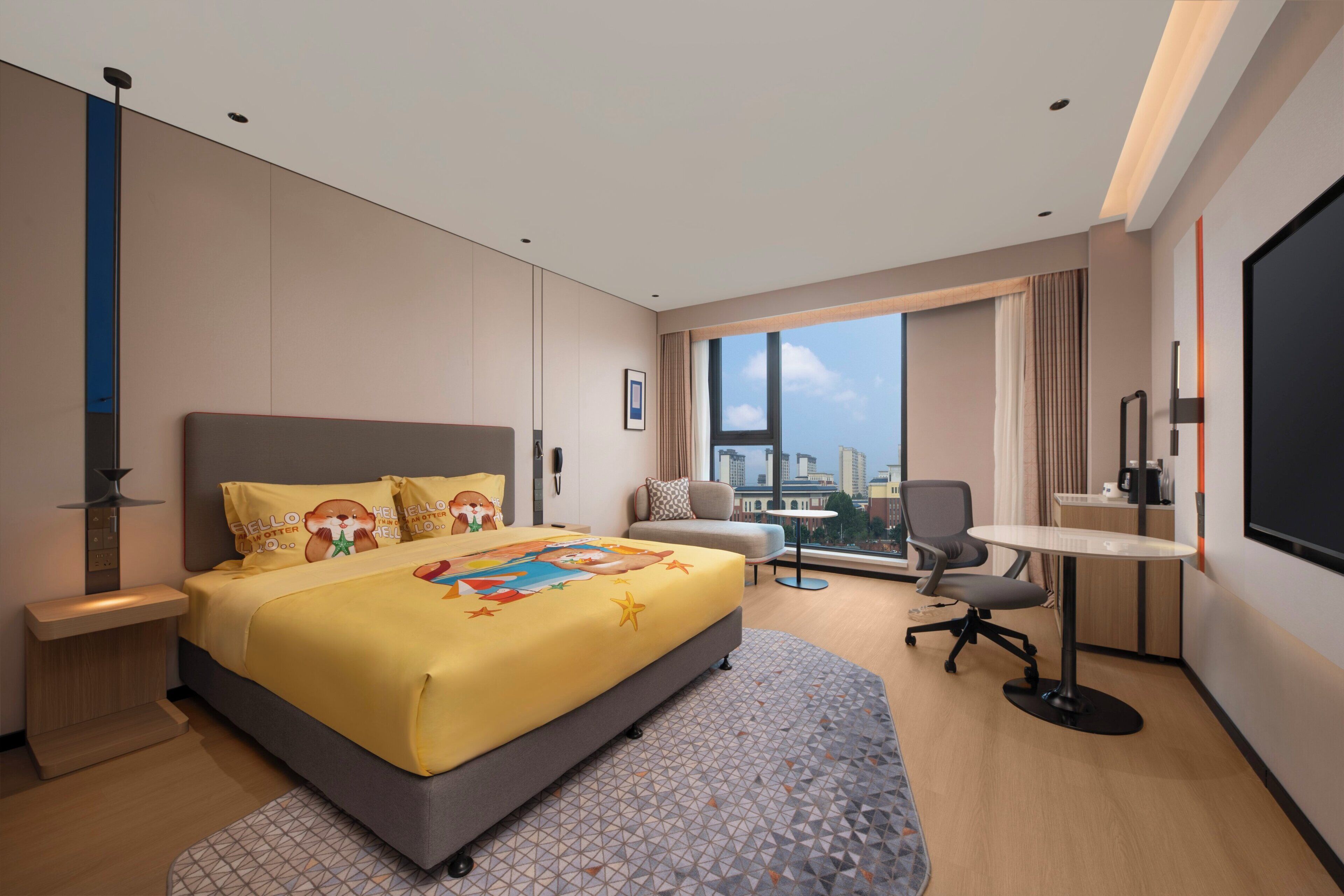 Habitación de hotel moderna con una cama grande, un escritorio, una silla y vistas a la ciudad.