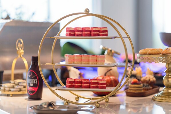 Un présentoir de desserts composé de trois étages de gâteaux et d’une bouteille de sirop au chocolat Hershey’s.