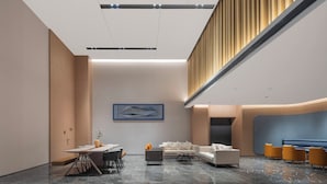 A modern hotel lobby with a marble floor, a reception desk, seating area, and a high ceiling with recessed lighting. - Holiday Inn Express Gongyi City Center by IHG (Zhengzhou)
