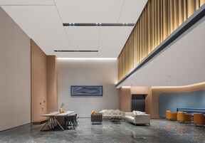 Un moderno vestíbulo de hotel con piso de mármol, un mostrador de recepción, zona de estar y un alto techo con iluminación empotrada.