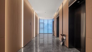 A modern hallway with a polished marble floor, wooden paneling on the walls, and a large window at the end. - Holiday Inn Express Gongyi City Center by IHG (Zhengzhou)