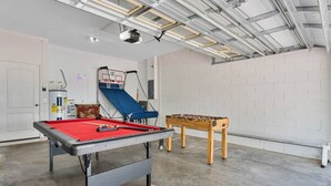 A recreational room with a pool table, a foosball table, and a ping pong table.